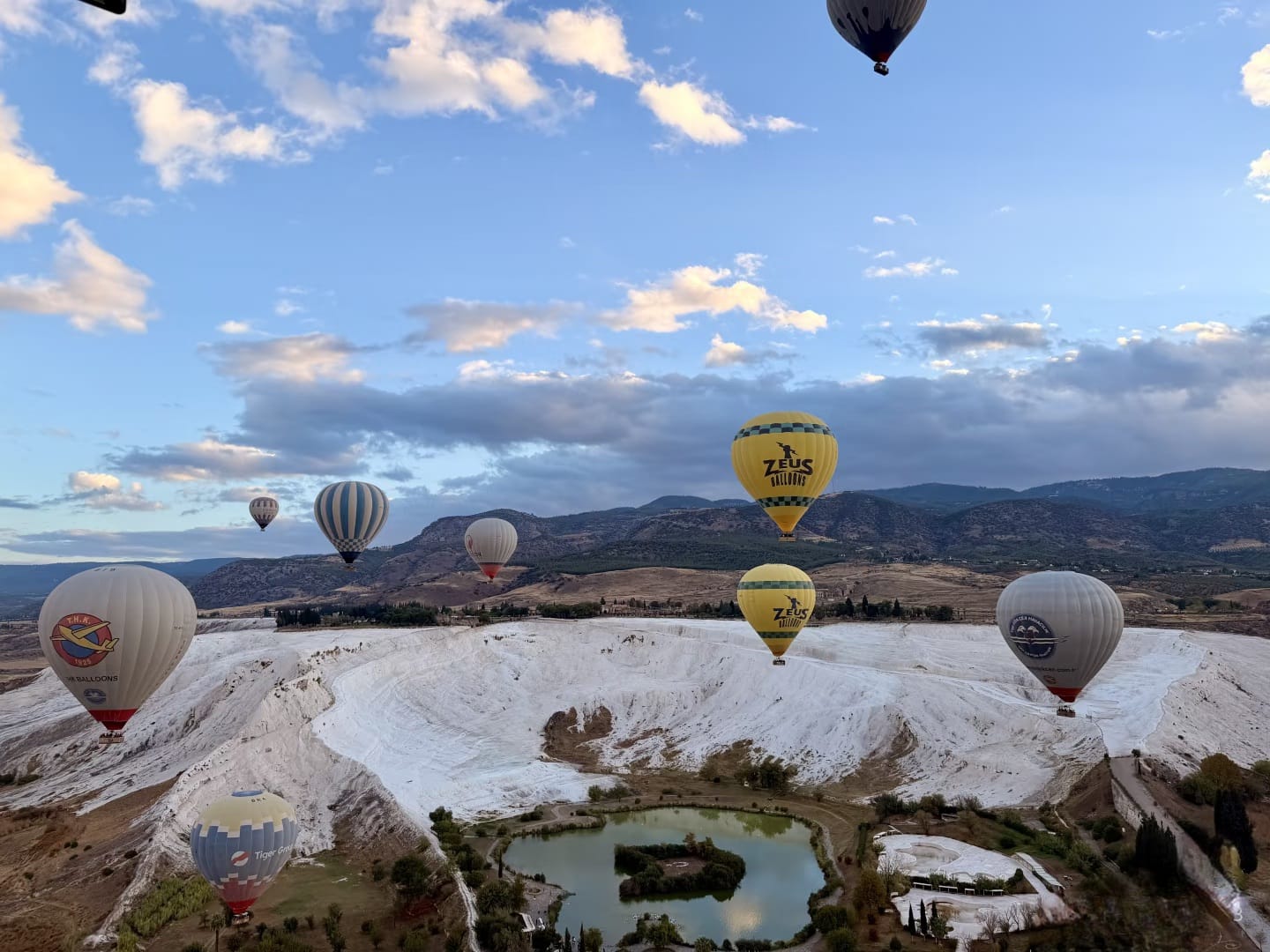 Hot air balloons over Pamukkale white travertine terraces at sunrise, Denizli Turkey